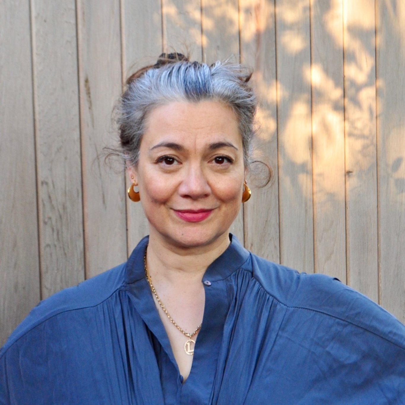 Photograph of Dr Liza Messing, Consultant Clinical Psychologist against a cedar wood background with natural light highlights.